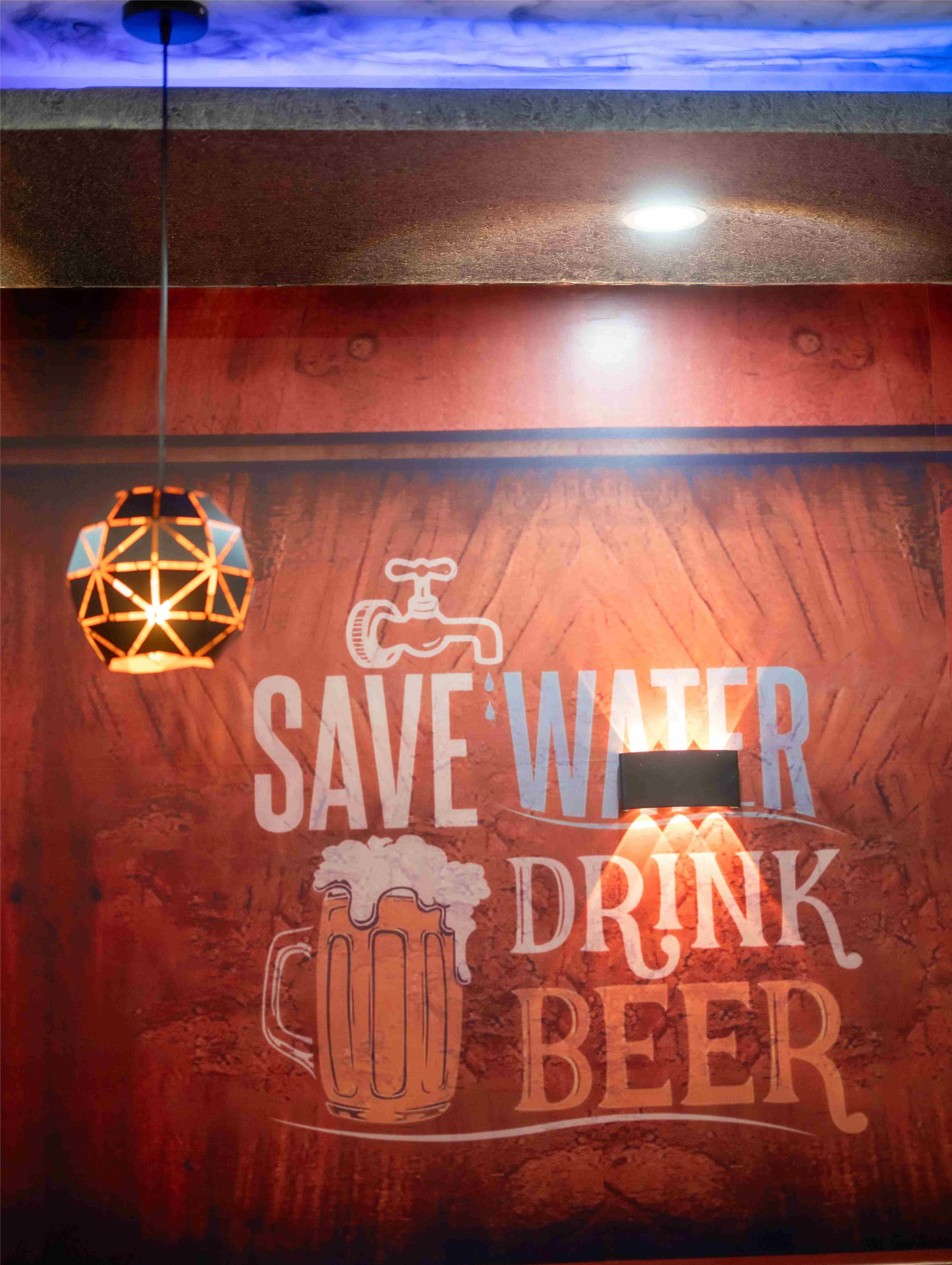 Elixir Hotel wall art with Save Water Drink Beer sign and hanging lamp